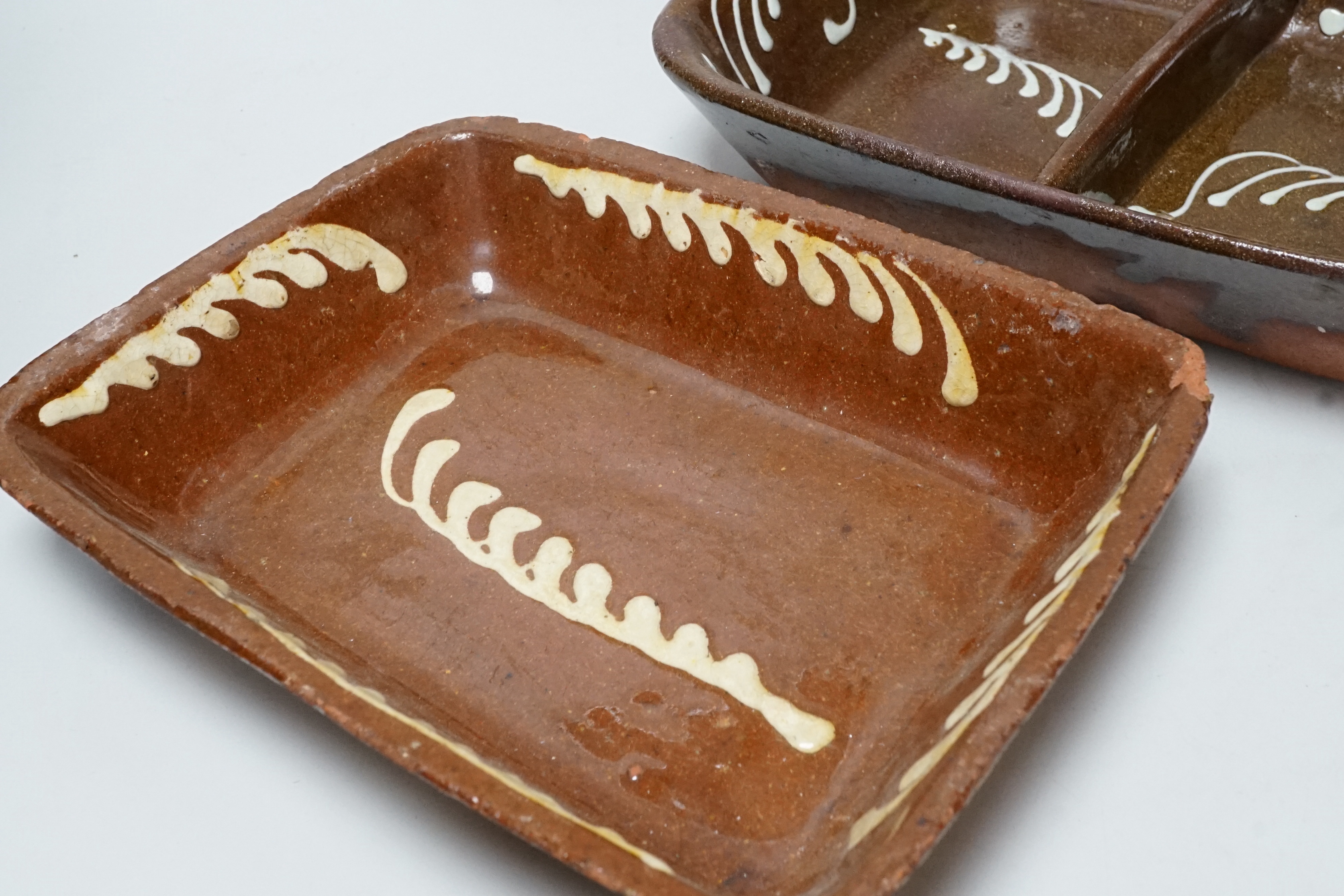 A 19th century slipware baking dish, 27cm wide, together with a twin division dish, 30cm